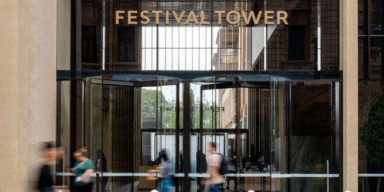 People walking outside one of the entrances to Festival Tower looking in towards the lobby